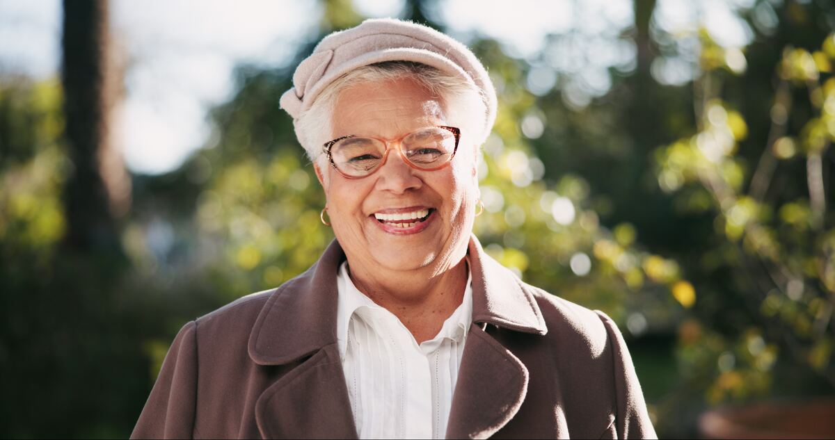A senior woman in a natural outdoor setting, soft afternoon light.