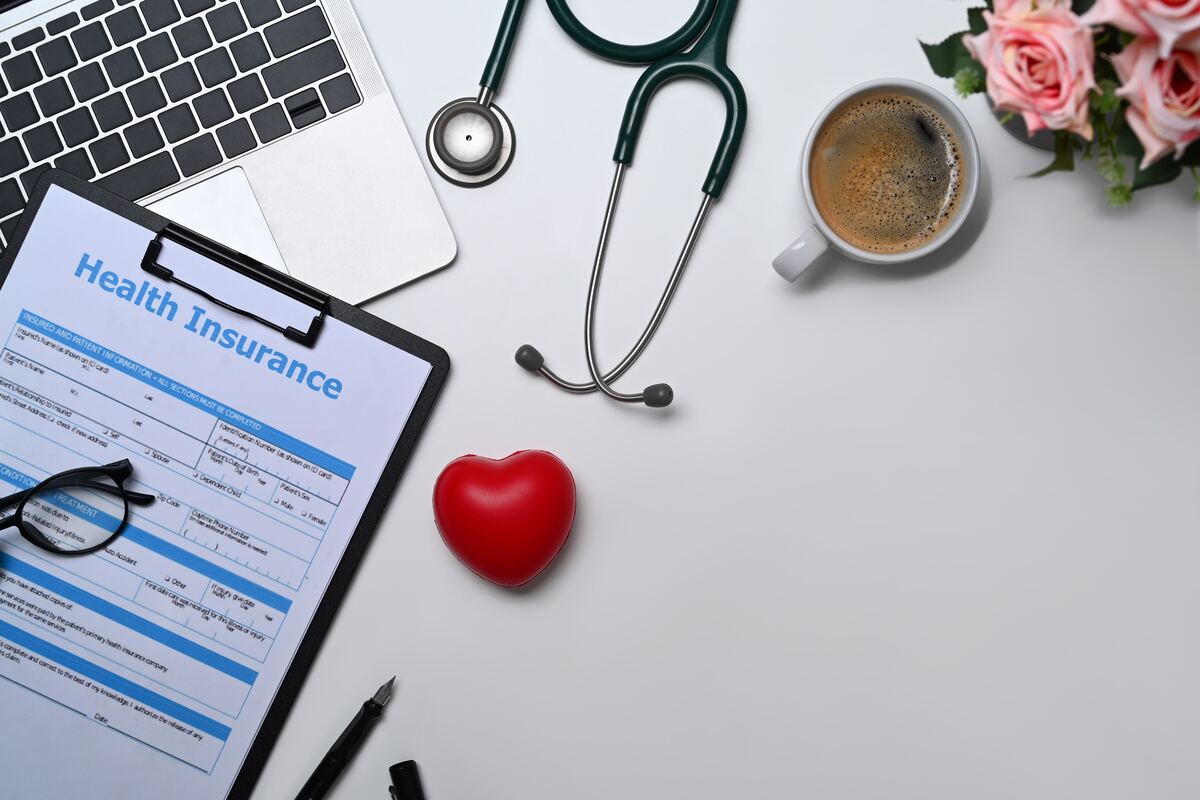 Una forma de seguro médico y un estetoscopio sobre un escritorio, con luz de mañana.